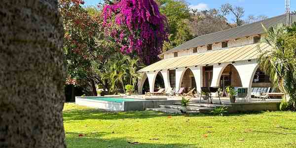 Original Lake House exterior beside the pool and flowering garden
